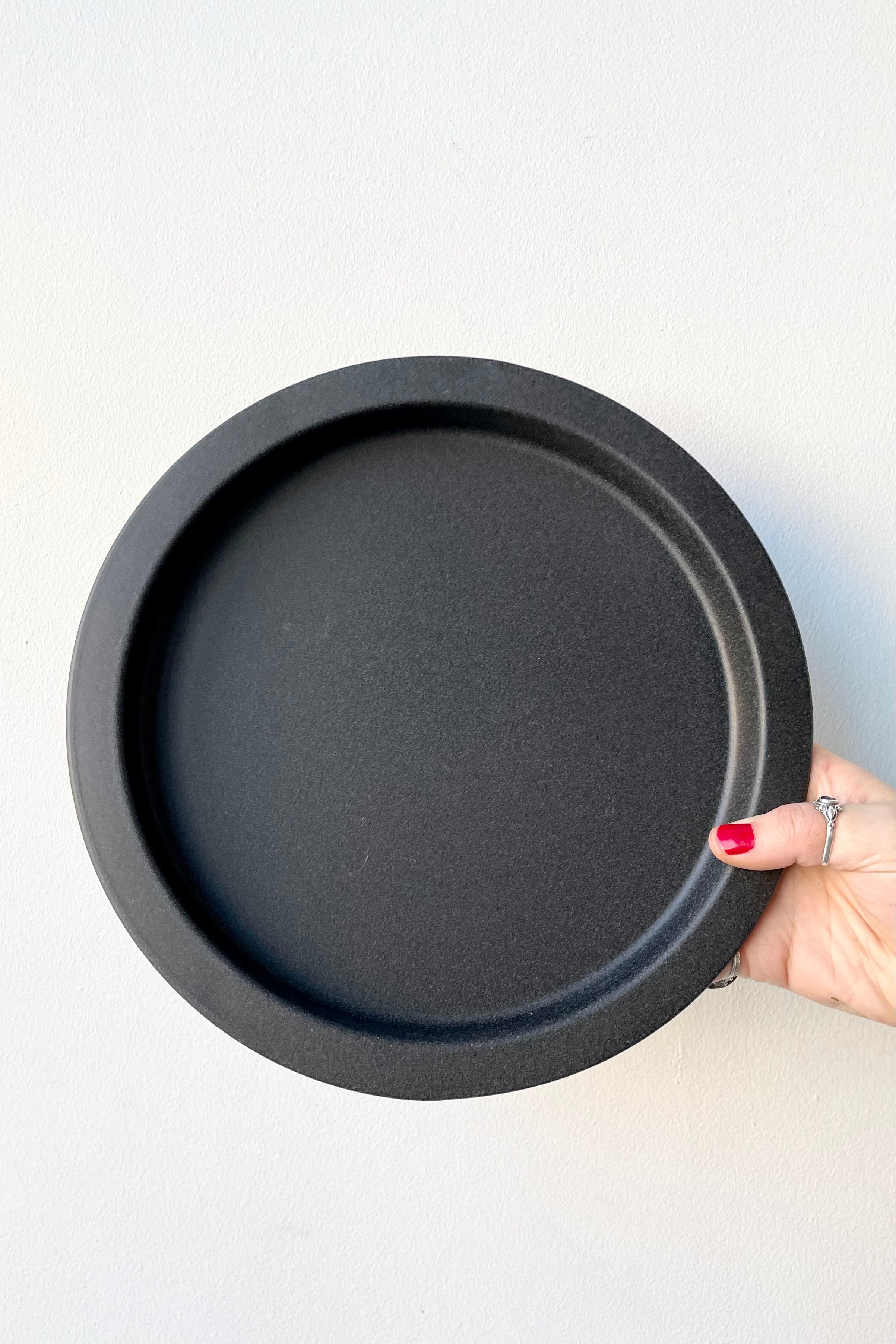 A speckled grey saucer held against a while wall at Sprout-home. 