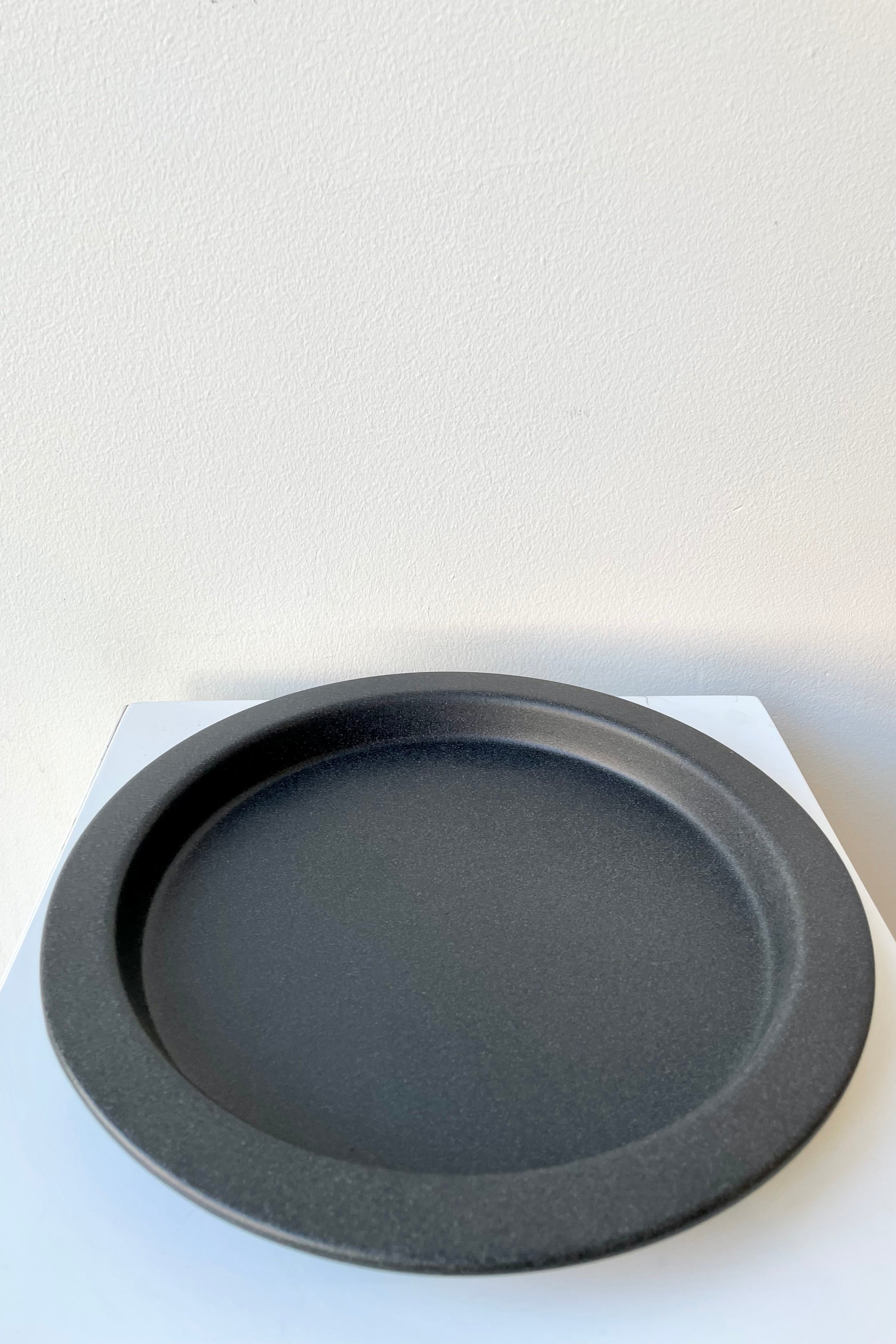 8" speckled grey saucer against a white wall at Sprout-home. 