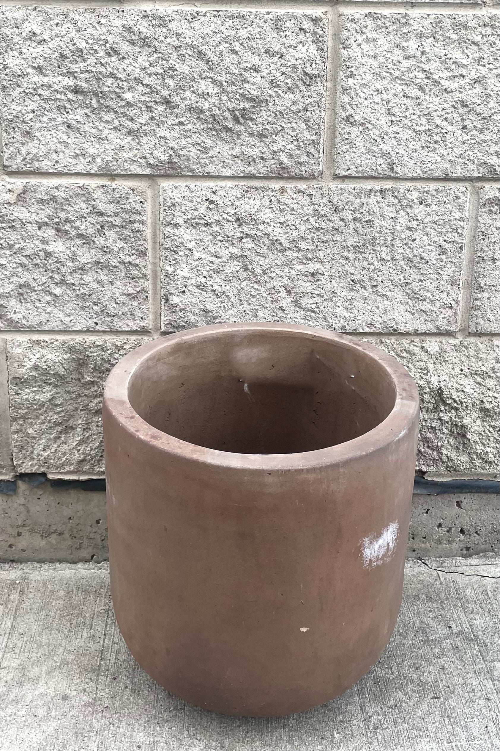 A slightly overhead view of Dora Planter Medium against concrete backdrop